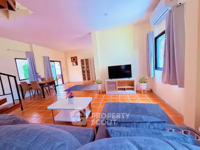 Spacious living room with modern decor and natural light, featuring a cozy seating area and dining space.