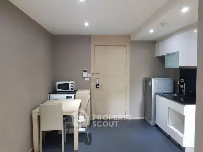 Modern compact kitchen with dining area and appliances in a cozy apartment.