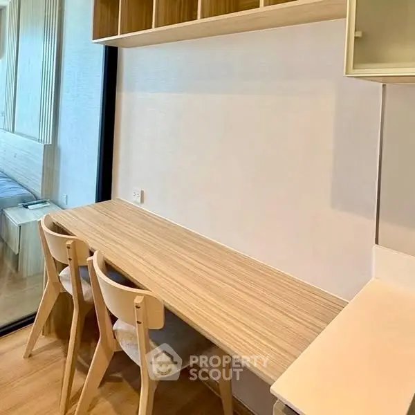 Modern study area with wooden desk and chairs, adjacent to a cozy bedroom.