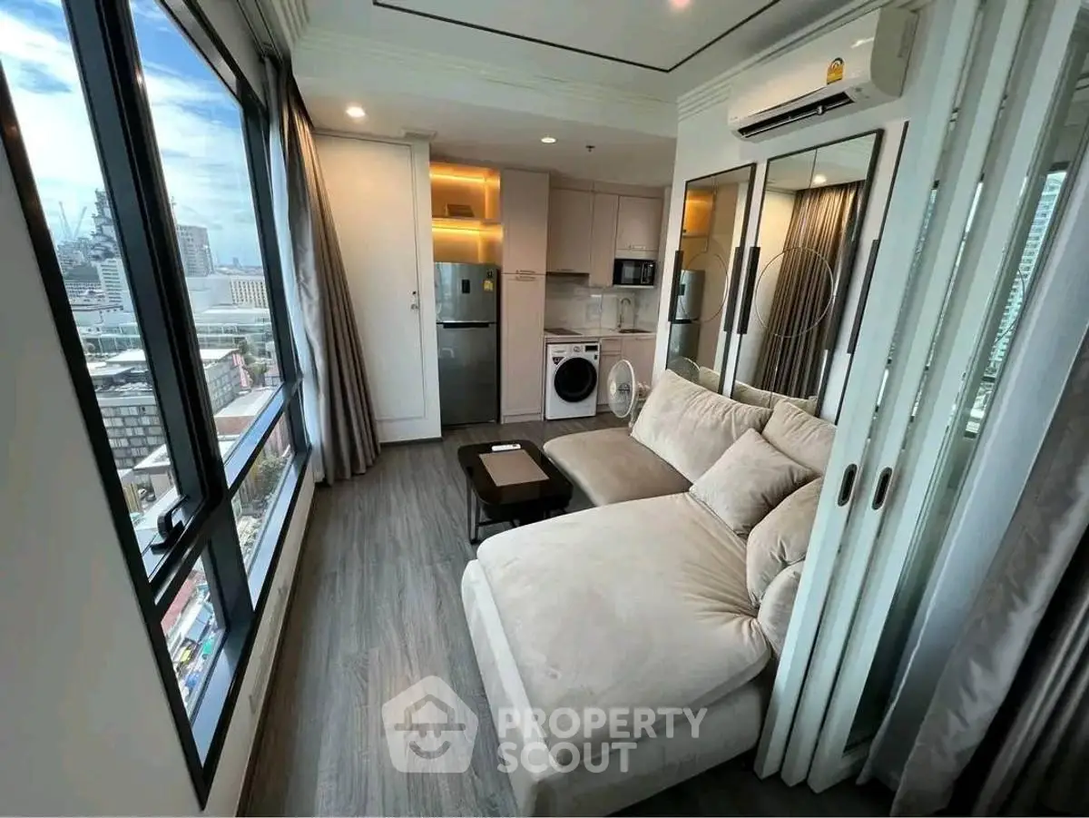 Modern living room with city view, featuring plush sofa and integrated kitchen appliances.