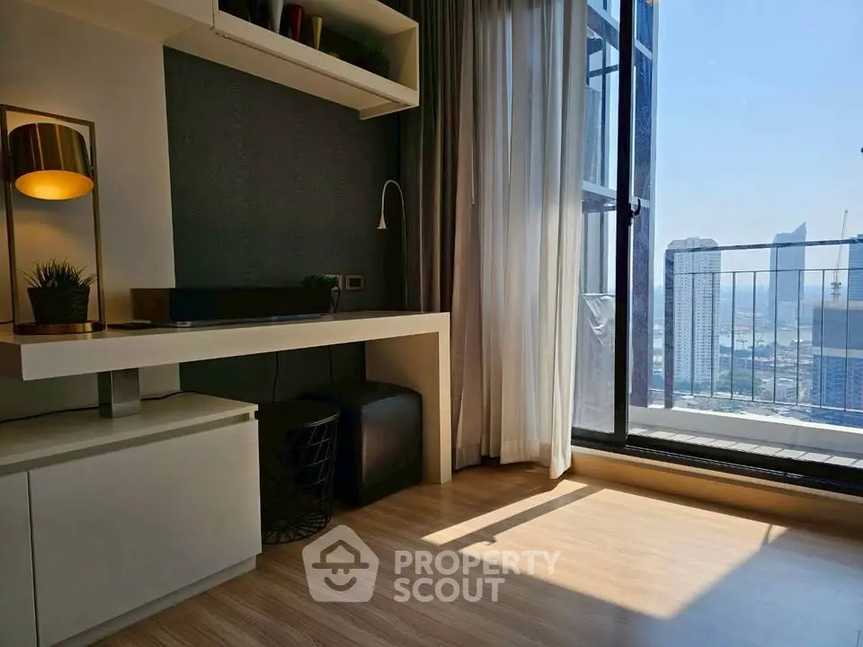 Modern living room with city view and balcony access, featuring sleek furniture and abundant natural light.