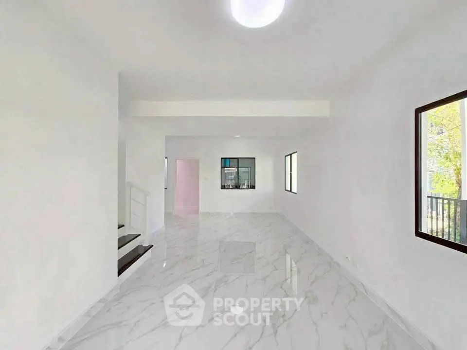 Spacious modern living room with marble flooring and ample natural light.