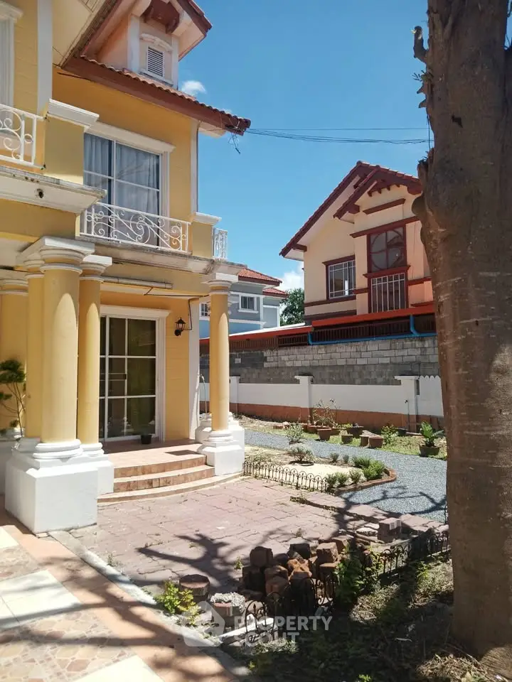 Charming two-story house with elegant columns and landscaped garden in a serene neighborhood.