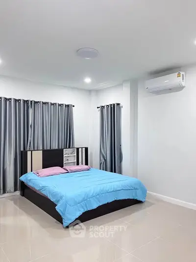 Modern bedroom with sleek design and air conditioning, featuring a cozy bed and stylish curtains.