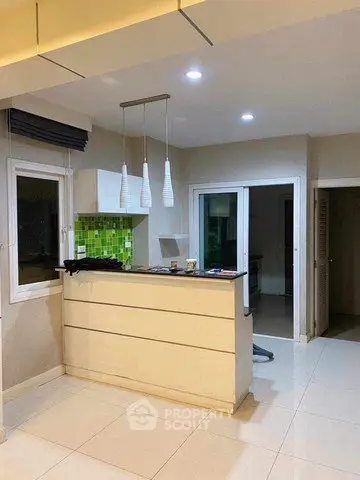 Modern kitchen with sleek design and green tile backsplash, featuring pendant lighting and open layout.