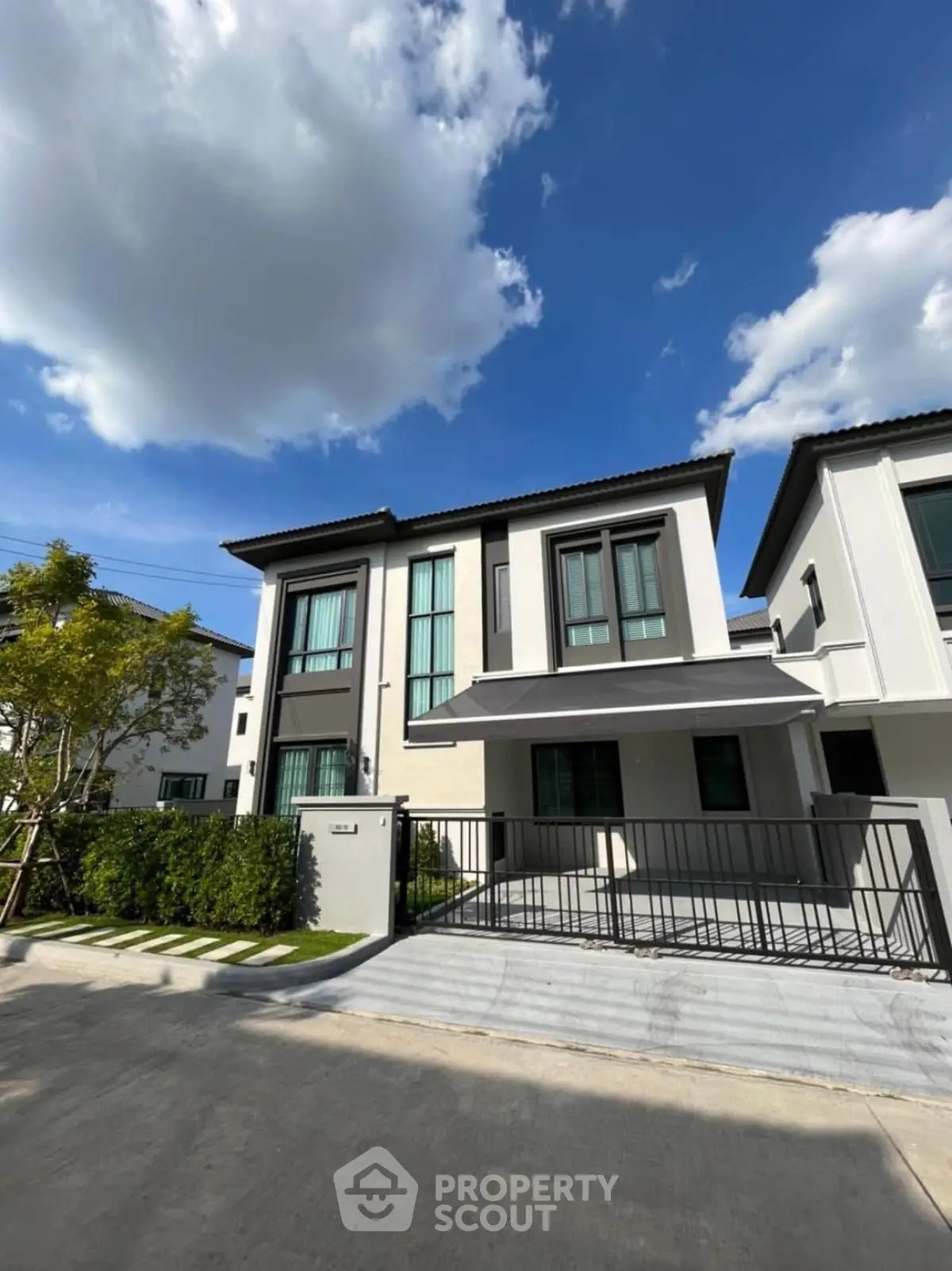 Modern two-story house with sleek design and spacious driveway under a clear blue sky.