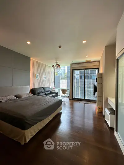Spacious modern studio with large windows and city view, featuring a cozy bed and stylish seating area.