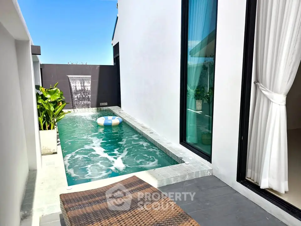 Luxurious private pool with modern design and waterfall feature in a contemporary villa setting.