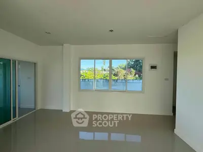 Spacious empty room with large window and glossy floor, perfect for customization.