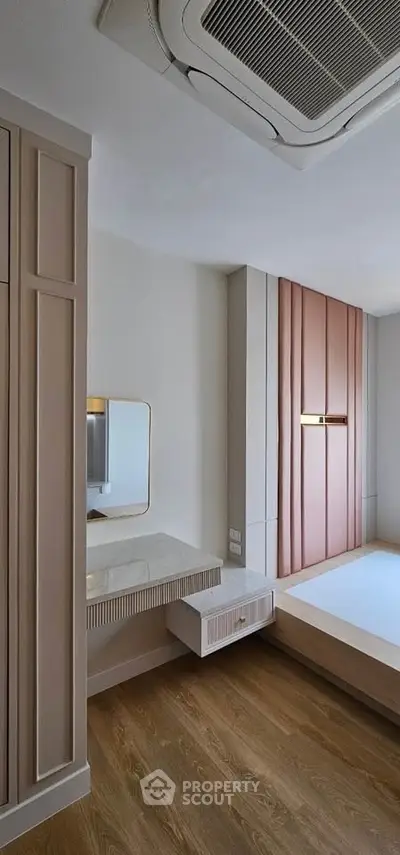 Modern bedroom with stylish wood flooring and built-in storage solutions.