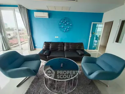 Modern living room with blue accent wall, stylish furniture, and large windows for natural light.