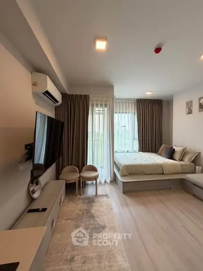 Modern studio apartment with cozy bed, large TV, and elegant decor.