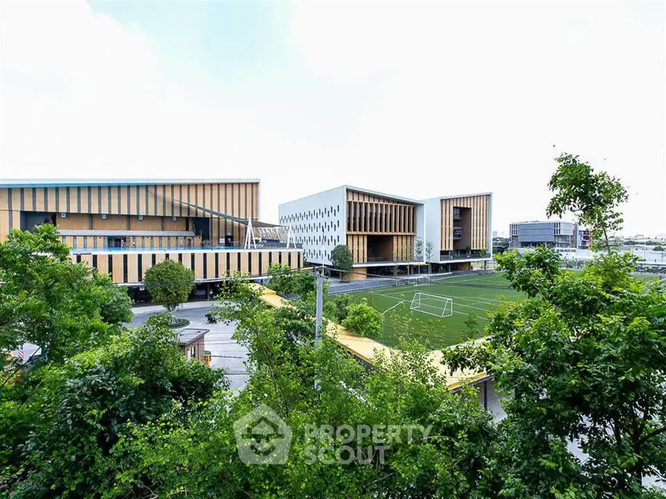 Modern educational building with sports field and lush greenery