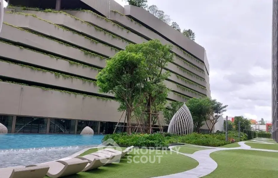 Luxurious modern building with lush garden and poolside relaxation area.