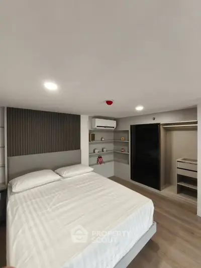 Modern bedroom with sleek design, featuring a comfortable bed, built-in shelves, and air conditioning.