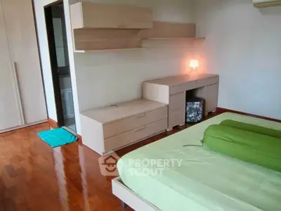 Spacious bedroom with modern wooden furniture and polished hardwood floors.