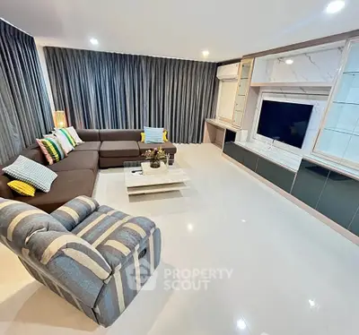 Spacious modern living room with stylish furniture and large TV setup.