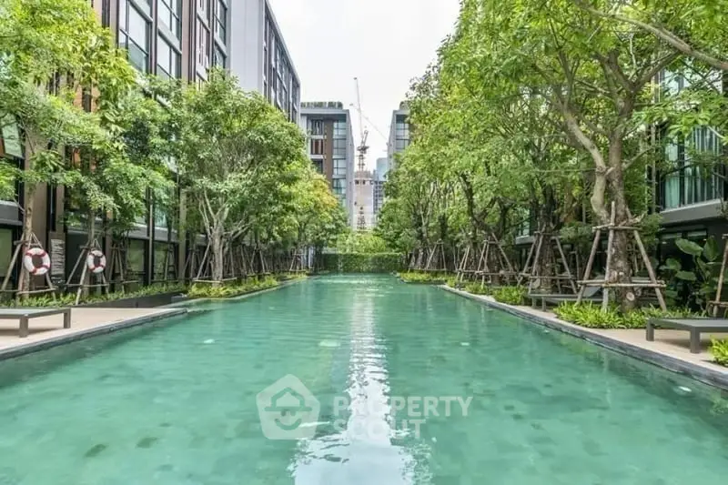 Luxurious residential complex with a stunning outdoor pool surrounded by lush greenery and modern architecture.