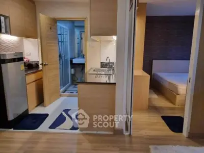 Modern apartment interior with kitchen and bedroom view, featuring sleek wooden finishes.