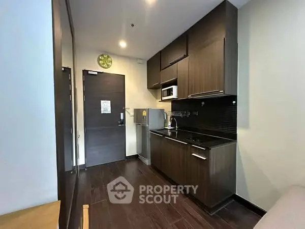 Modern compact kitchen with dark wood cabinets and sleek appliances