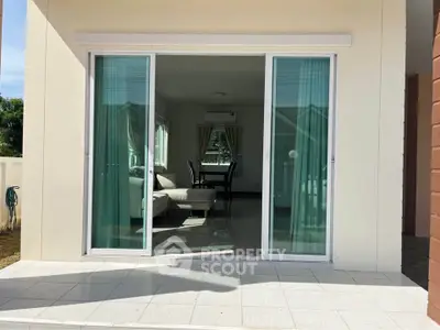 Modern living room with sliding glass doors opening to a bright patio, showcasing elegant interior design.