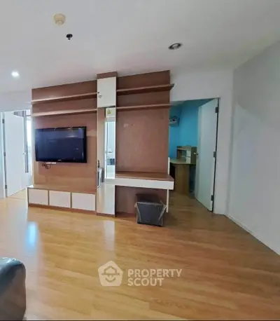 Spacious living room with wooden flooring and built-in TV unit in modern apartment.