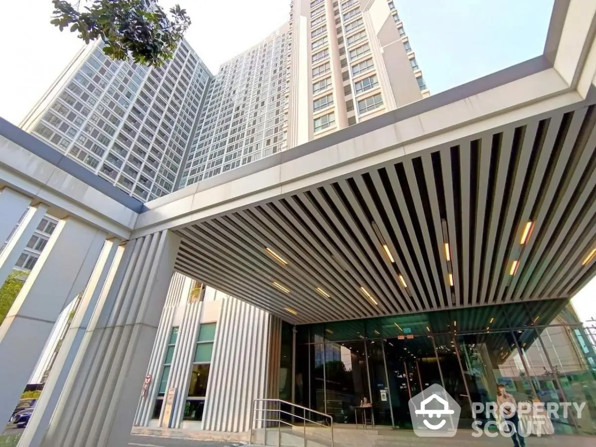 Modern high-rise building entrance with sleek architectural design and glass facade.