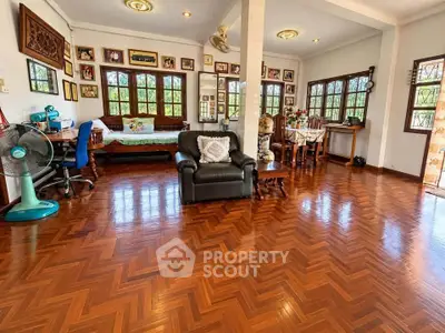 Spacious living room with wooden flooring and abundant natural light, perfect for family gatherings.