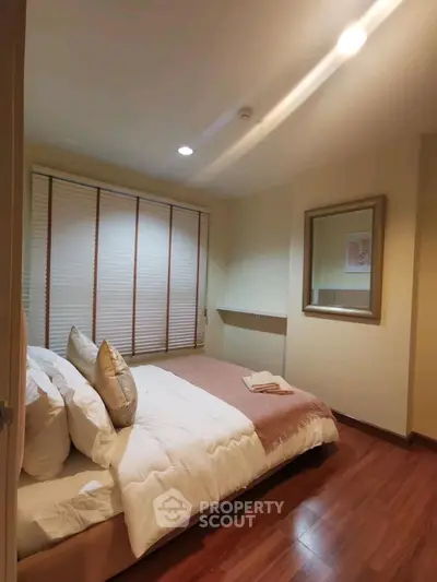 Cozy bedroom with wooden flooring and soft lighting, perfect for relaxation.