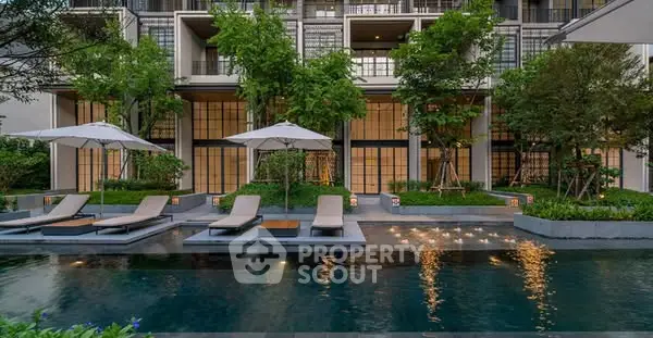 Luxurious modern apartment complex with poolside relaxation area and lush greenery.