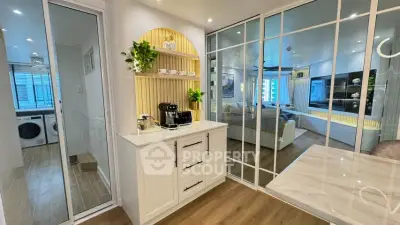 Modern kitchen with sleek design, featuring a coffee station and view into a stylish living room.