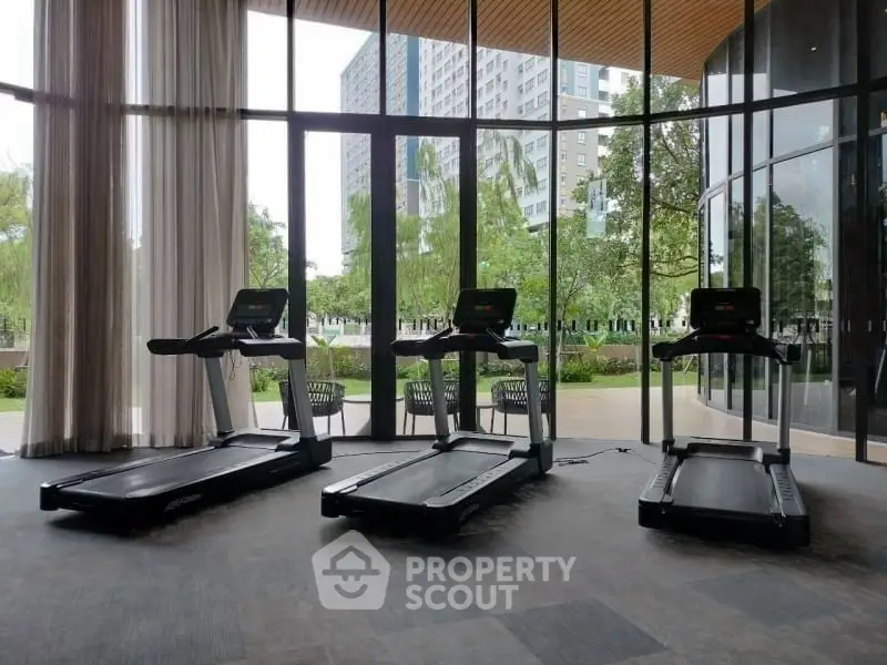 Modern gym with treadmills and large windows offering scenic views in a luxury apartment building.