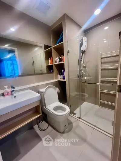 Modern bathroom with glass shower and sleek fixtures in contemporary apartment.