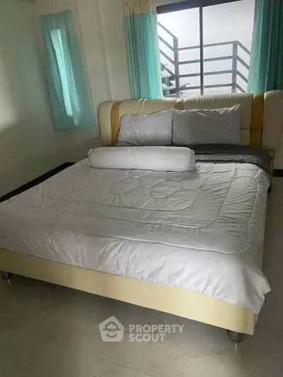 Cozy bedroom with modern bed and large window offering natural light and serene ambiance.
