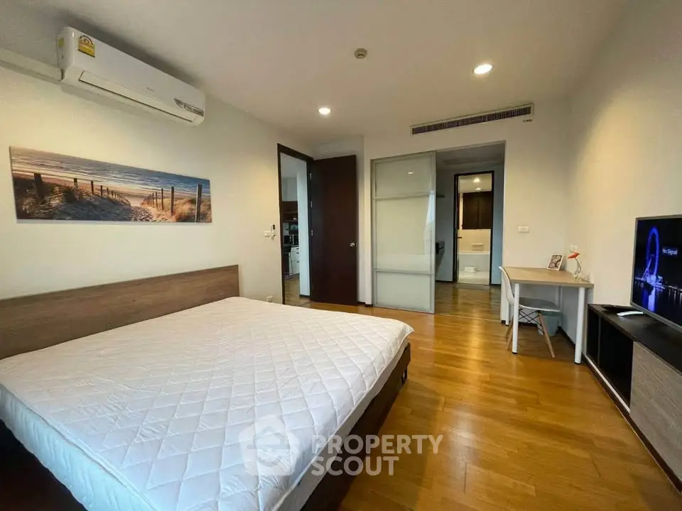 Spacious bedroom with modern decor and wooden flooring in a stylish apartment.