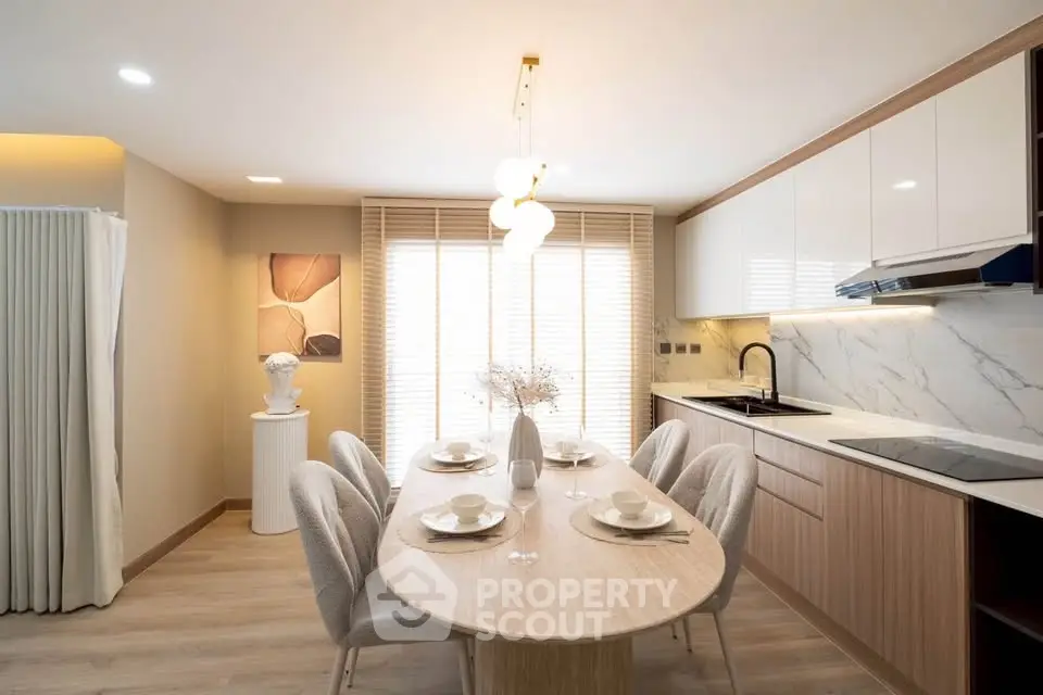 Modern kitchen with elegant dining area, featuring sleek cabinetry and stylish lighting.