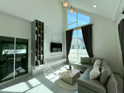 Spacious modern living room with high ceilings and large windows, featuring elegant decor and ample natural light.