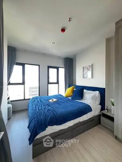 Modern bedroom with large windows and stylish decor in a high-rise apartment.