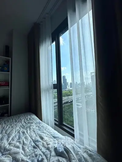 Cozy bedroom with stunning city view through large window and sheer curtains