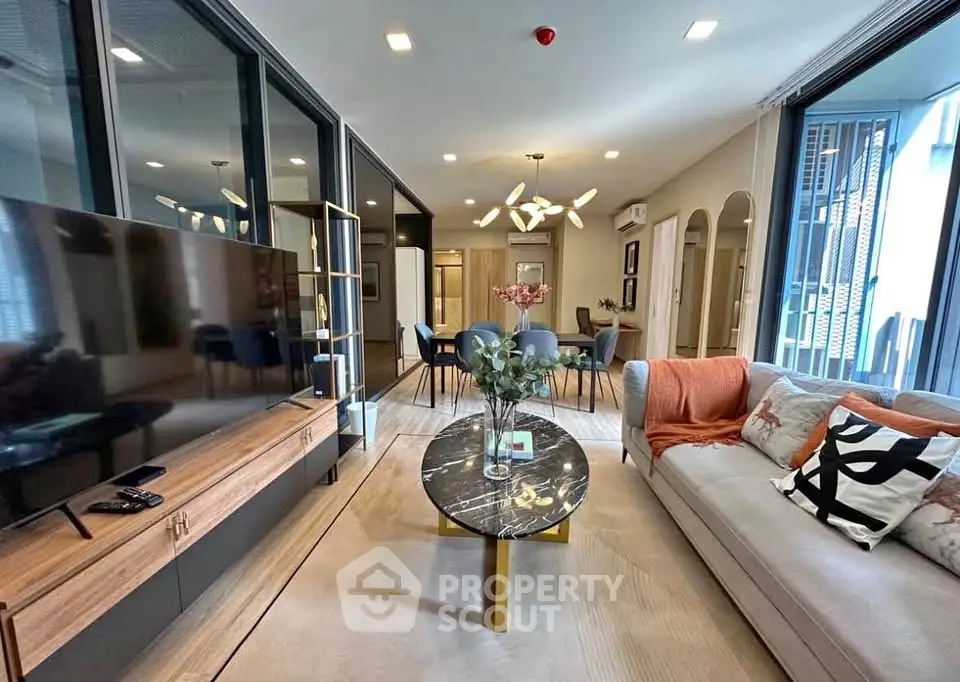 Luxurious modern living room with elegant decor and open layout, featuring a stylish marble coffee table and large TV.