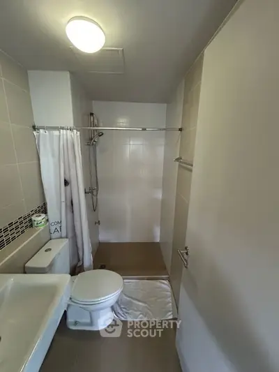 Modern bathroom with shower, toilet, and sink in neutral tones.