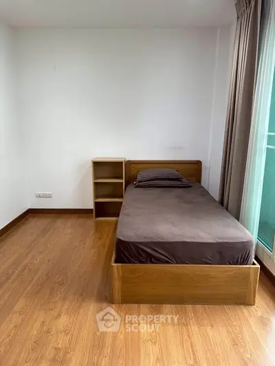 Cozy minimalist bedroom with wooden flooring and single bed near window.