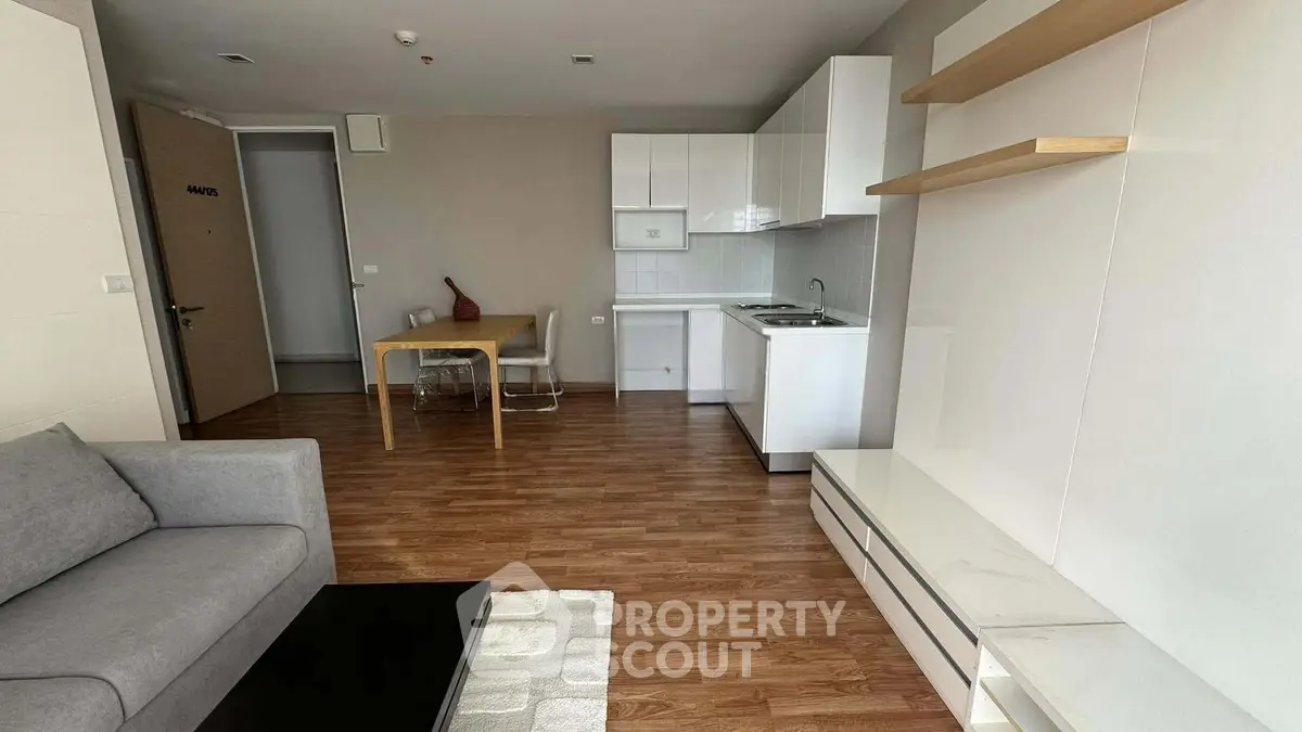 Modern open-plan living room with sleek kitchen and wooden flooring in a stylish apartment.