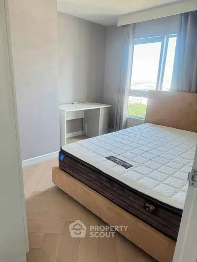 Modern bedroom with natural light, featuring a comfortable bed and a study desk by the window.