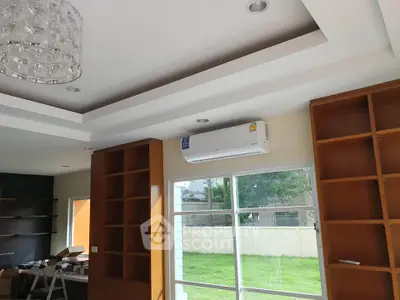 Spacious living room with built-in shelves and large window overlooking garden