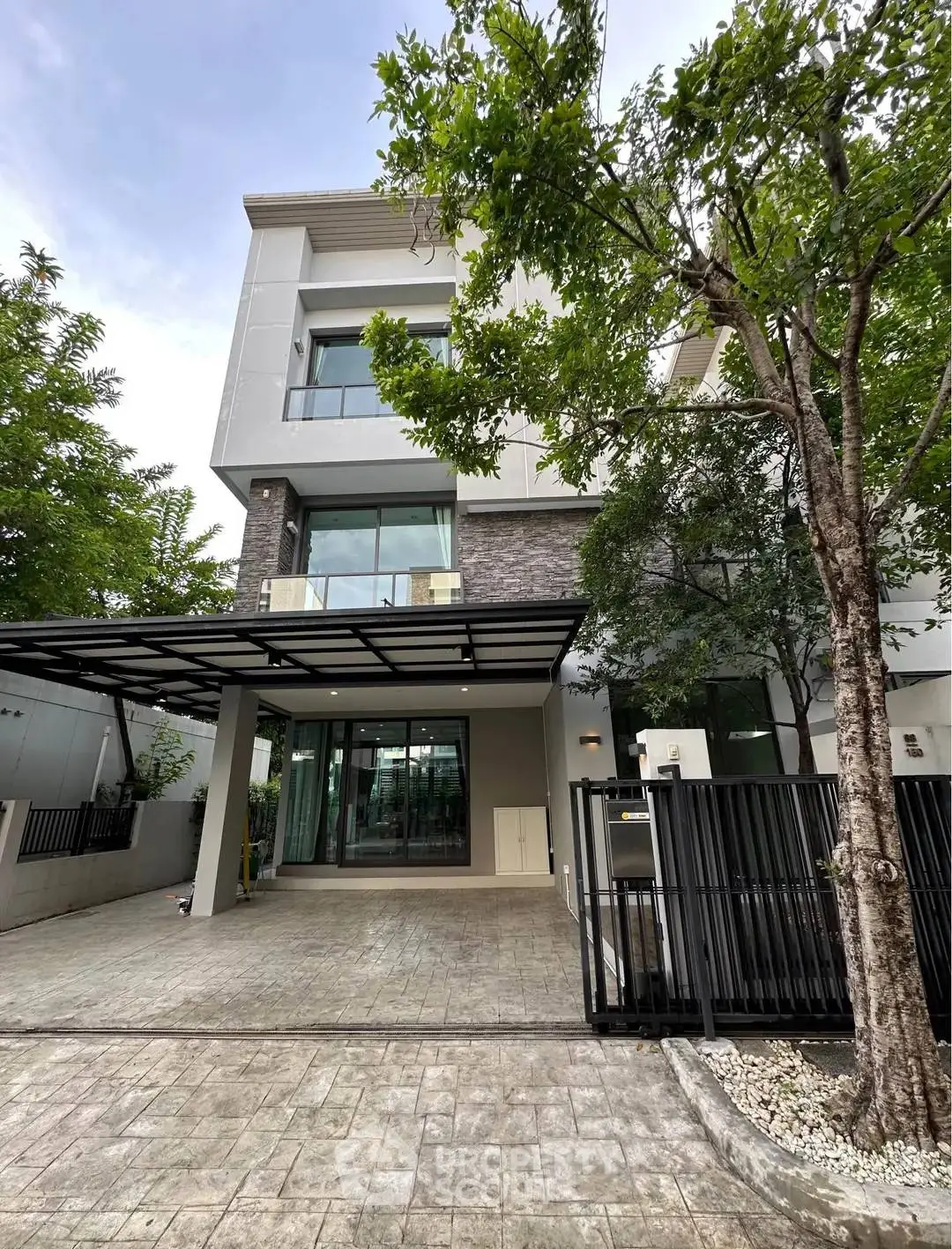 Modern three-story house with large windows and spacious driveway
