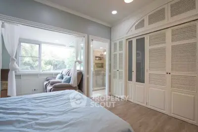 Spacious bedroom with large windows and cozy seating area, perfect for relaxation.
