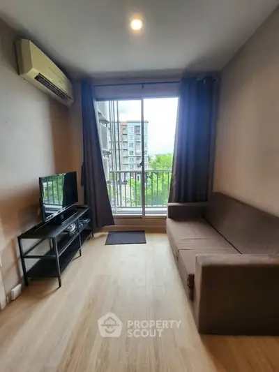 Cozy living room with balcony view, featuring modern sofa and TV setup.