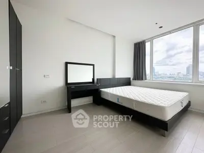 Spacious modern bedroom with city view, featuring sleek black furniture and large window.