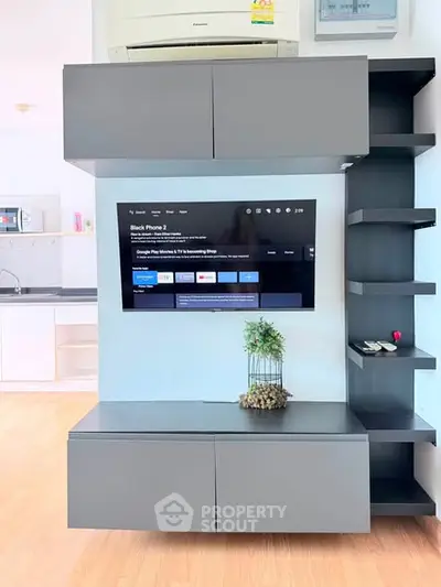 Modern living room with sleek TV unit and open kitchen layout, showcasing contemporary design and functionality.